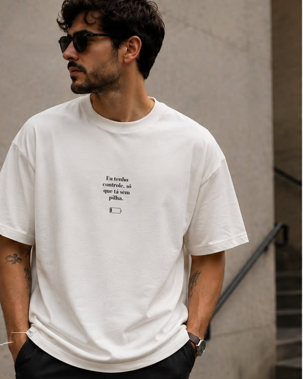 Camiseta offwhite Eu Tenho Controle com texto serifado e ícone de bateria no peito