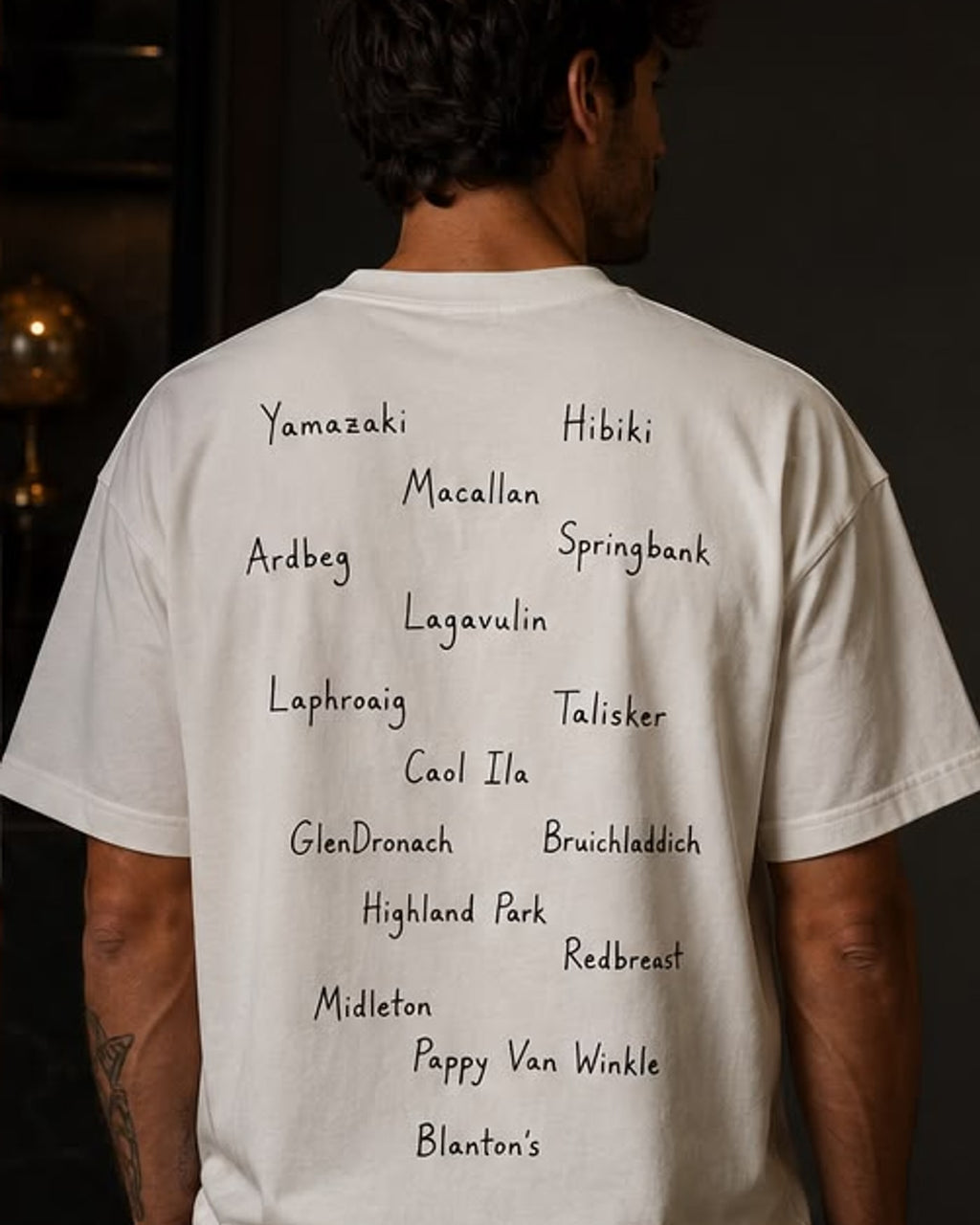 Costas da camiseta offwhite com lista manuscrita de destilarias de whisky